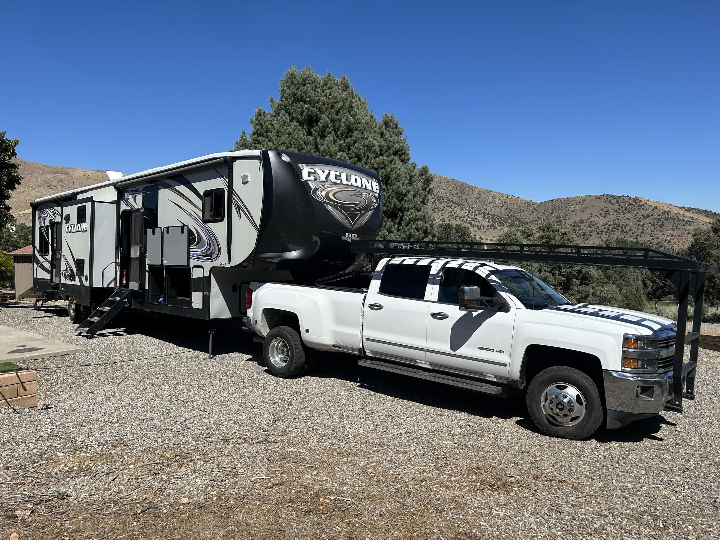 Fifth-wheel toyhauler and tow truck parked against Alpine County mountain backdrop