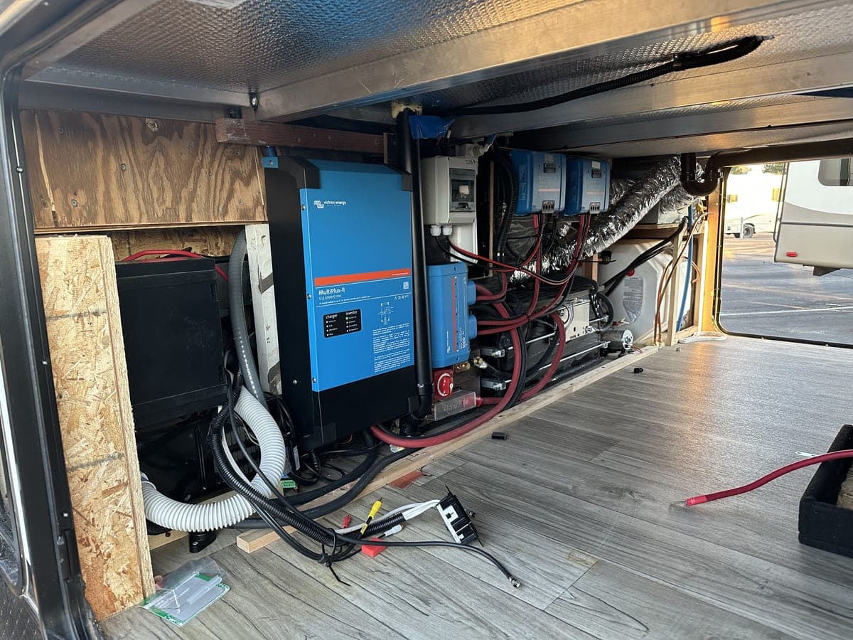Hidden 12V lithium battery bank and Victron system in toyhauler fifth-wheel under-compartment — adds system capability while preserving storage space